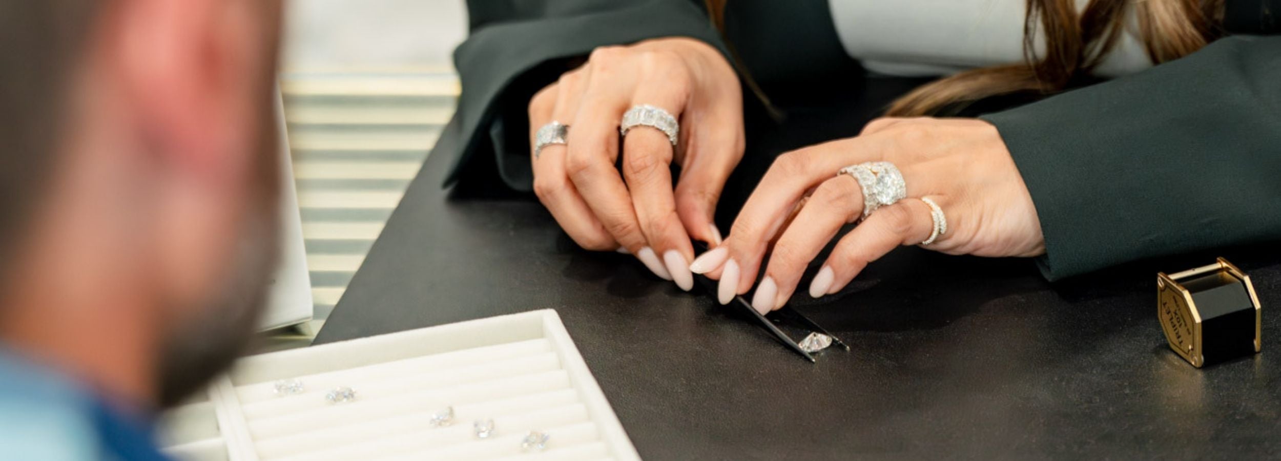 Jewelry consultant smiling with a client while reviewing pieces together at a showroom table.