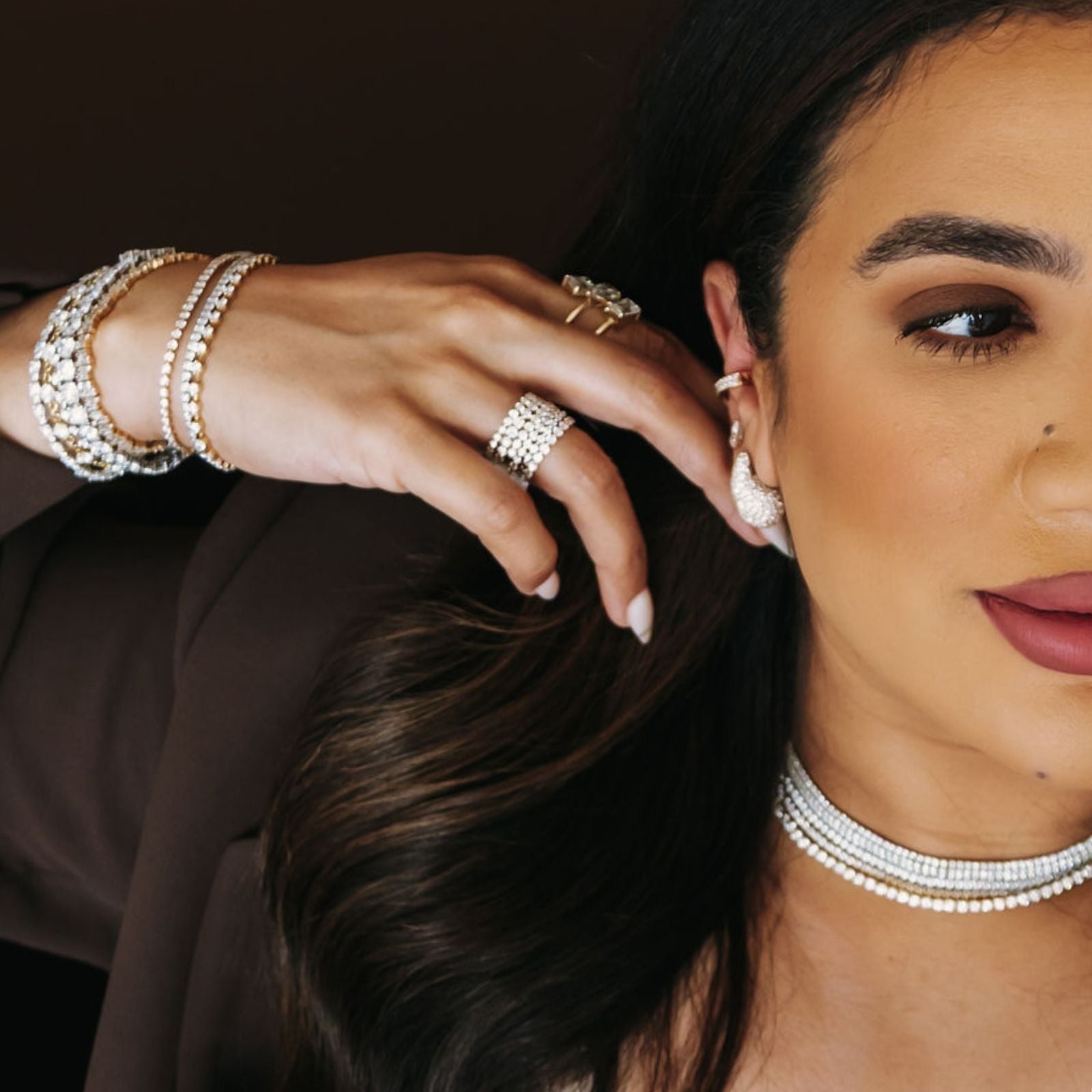 Close-up of a woman wearing jewelry including earrings, rings, and bracelets.