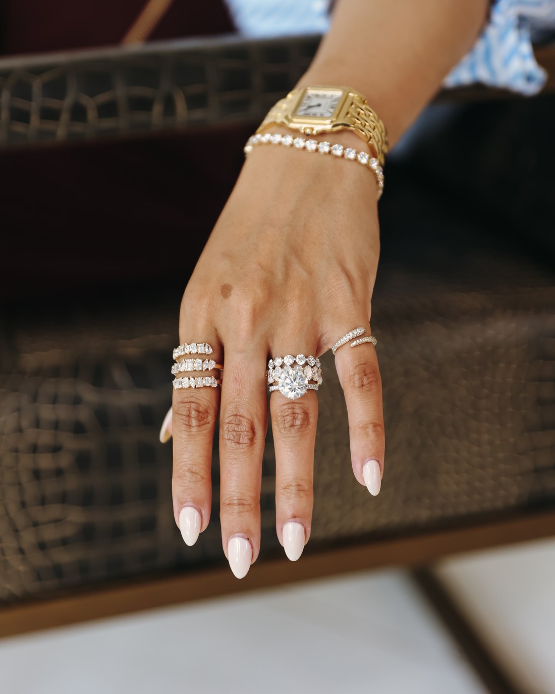 A hand on a leather chair wearing the Mixed-Shape Wrap Ring and the Signature Pavé Pinky Ring
