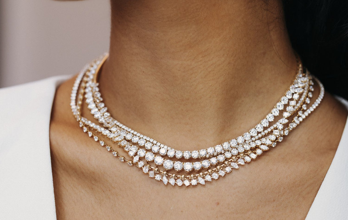 Layered diamond collar necklaces worn with a white V-neck